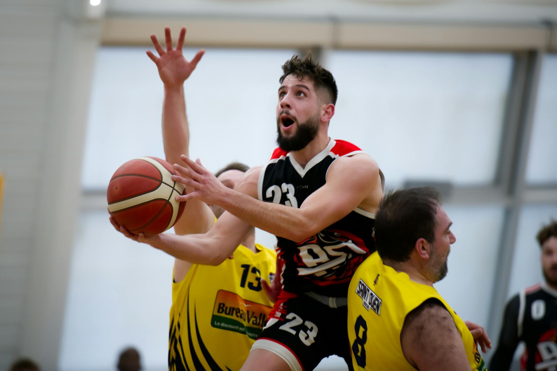 Dynamic indoor basketball action with players vying for the ball and scoring opportunity.