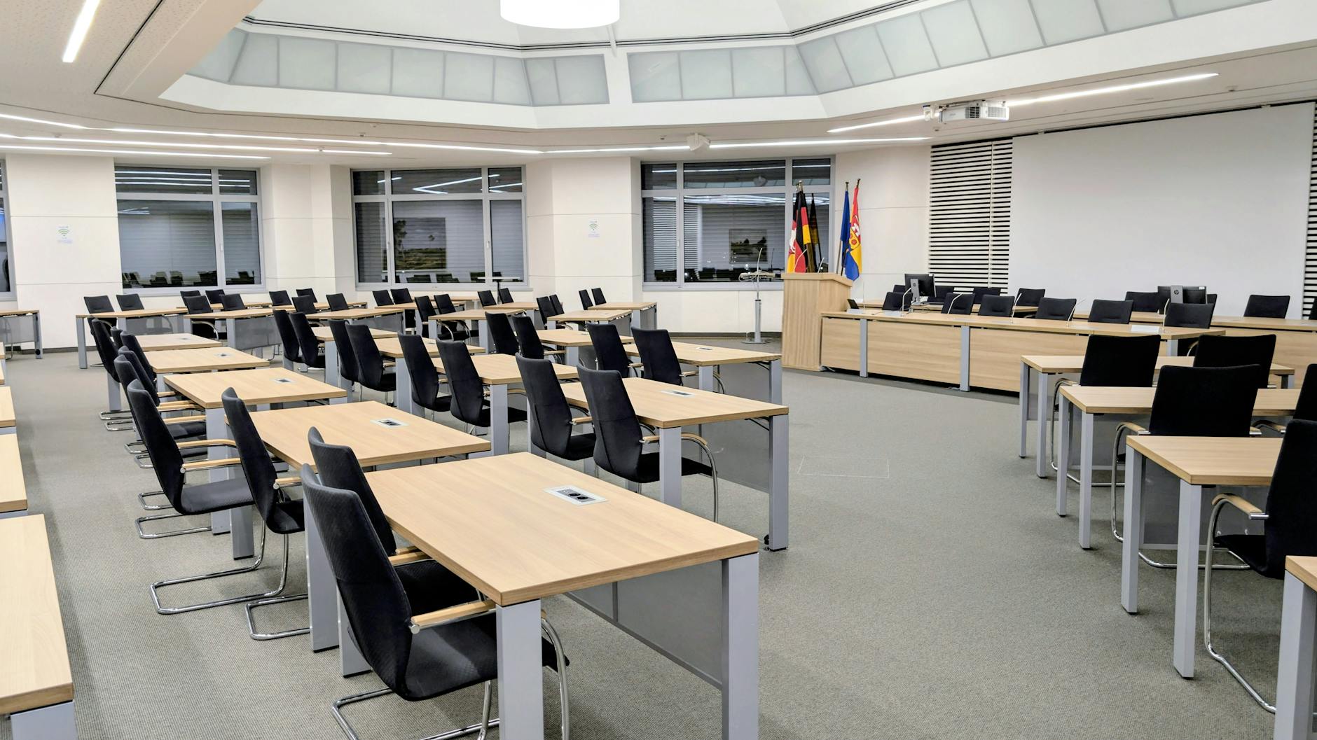 Spacious and modern meeting room in Niedersachsen, Germany, with desks and flags.