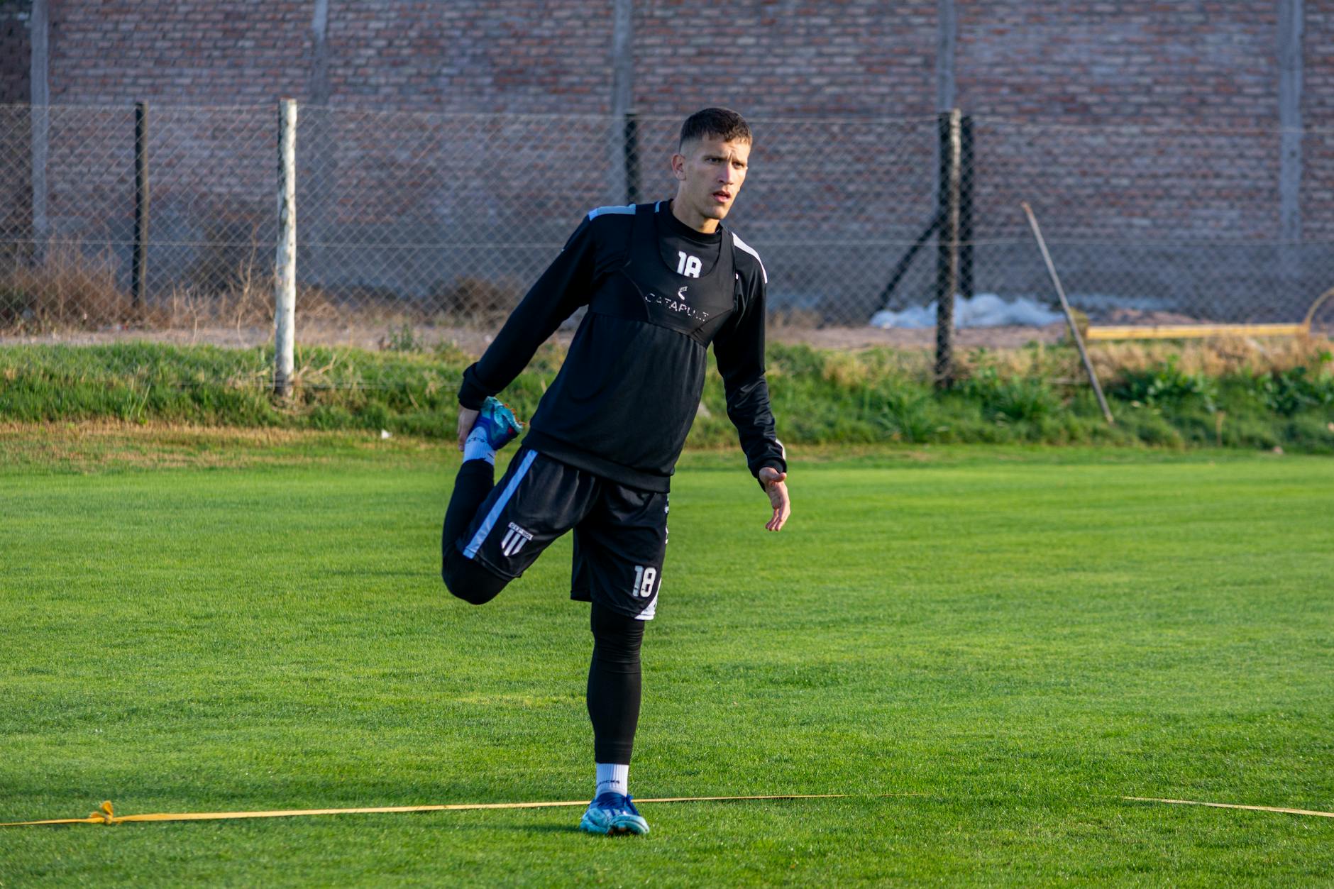 A football player stretching outdoors on the field during training for improved performance.