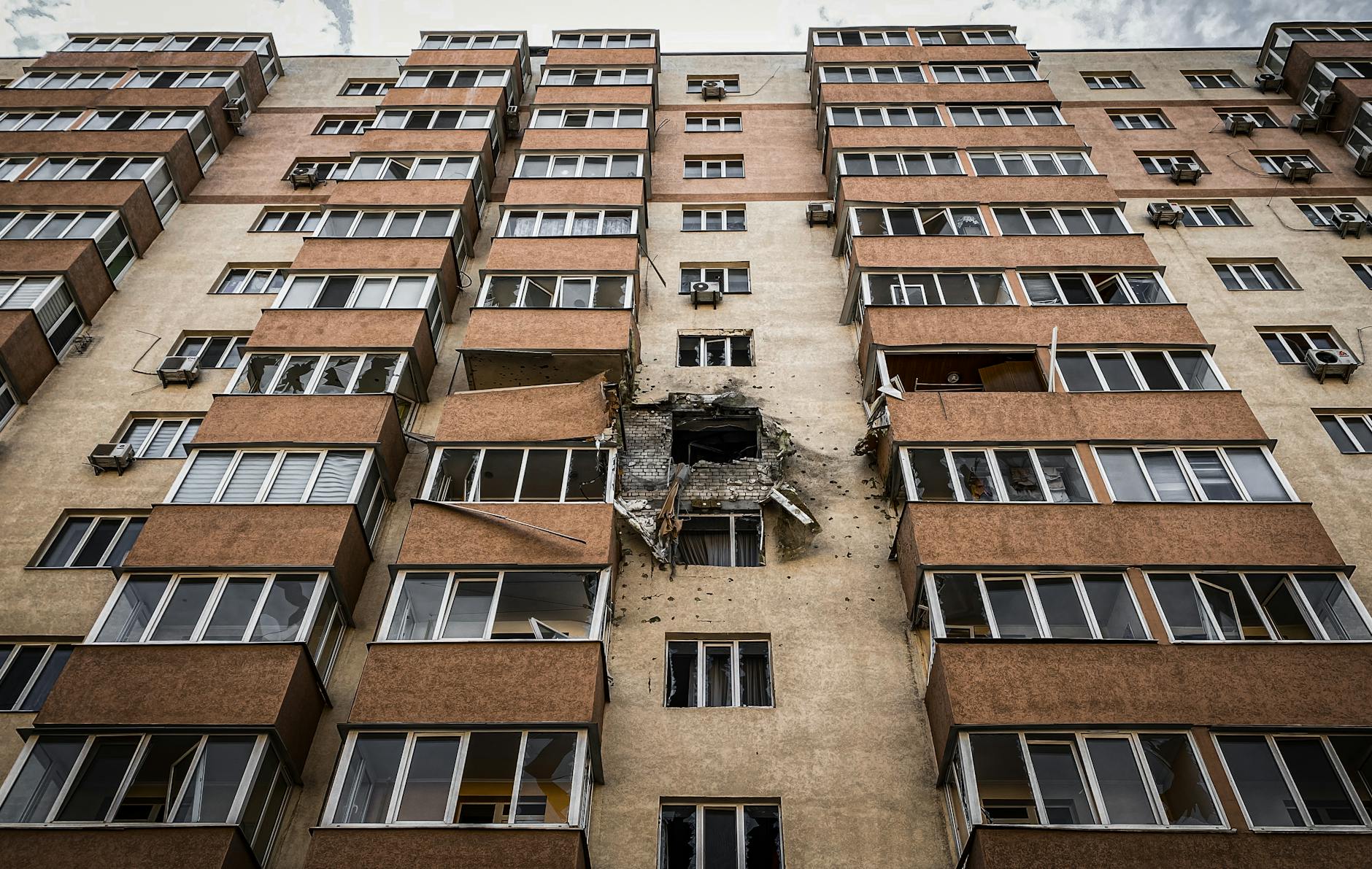 Low-angle view of a damaged apartment building in Kyiv, Ukraine with visible destruction.