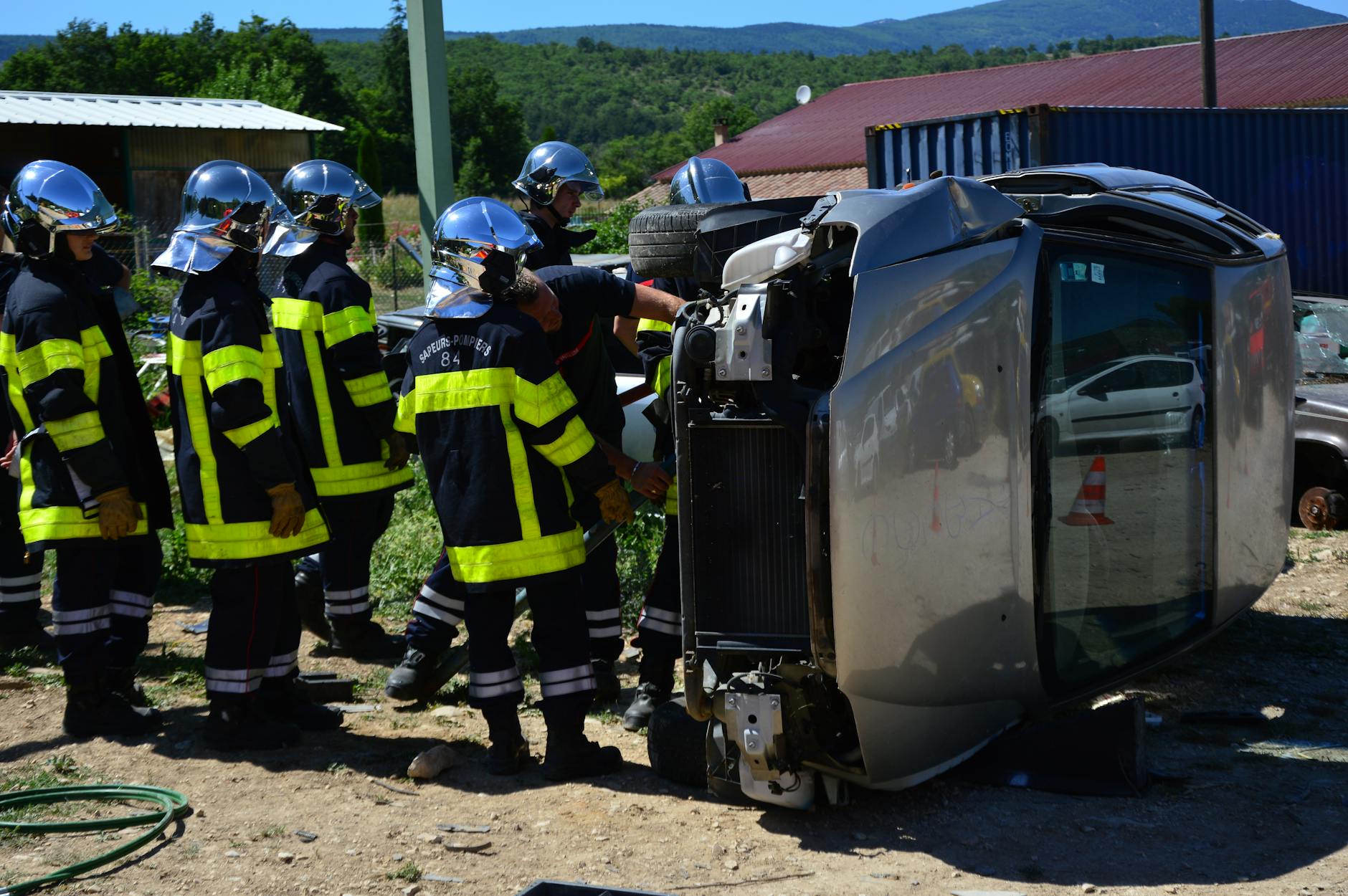 Firefighters attending to an overturned vehicle at an accident scene. Daylight outdoor operation.