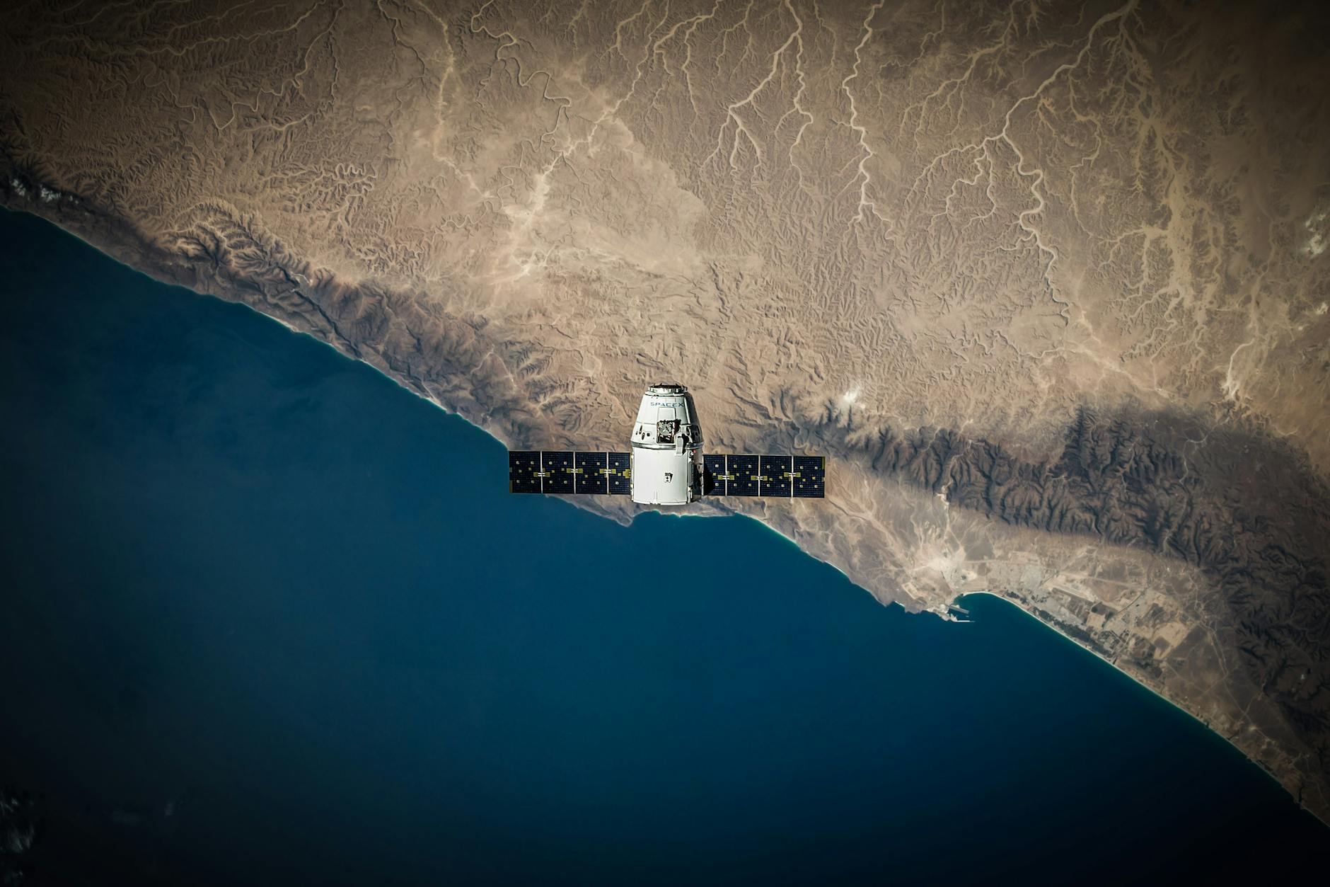 A satellite hovering above Earth's coastline, captured from space.