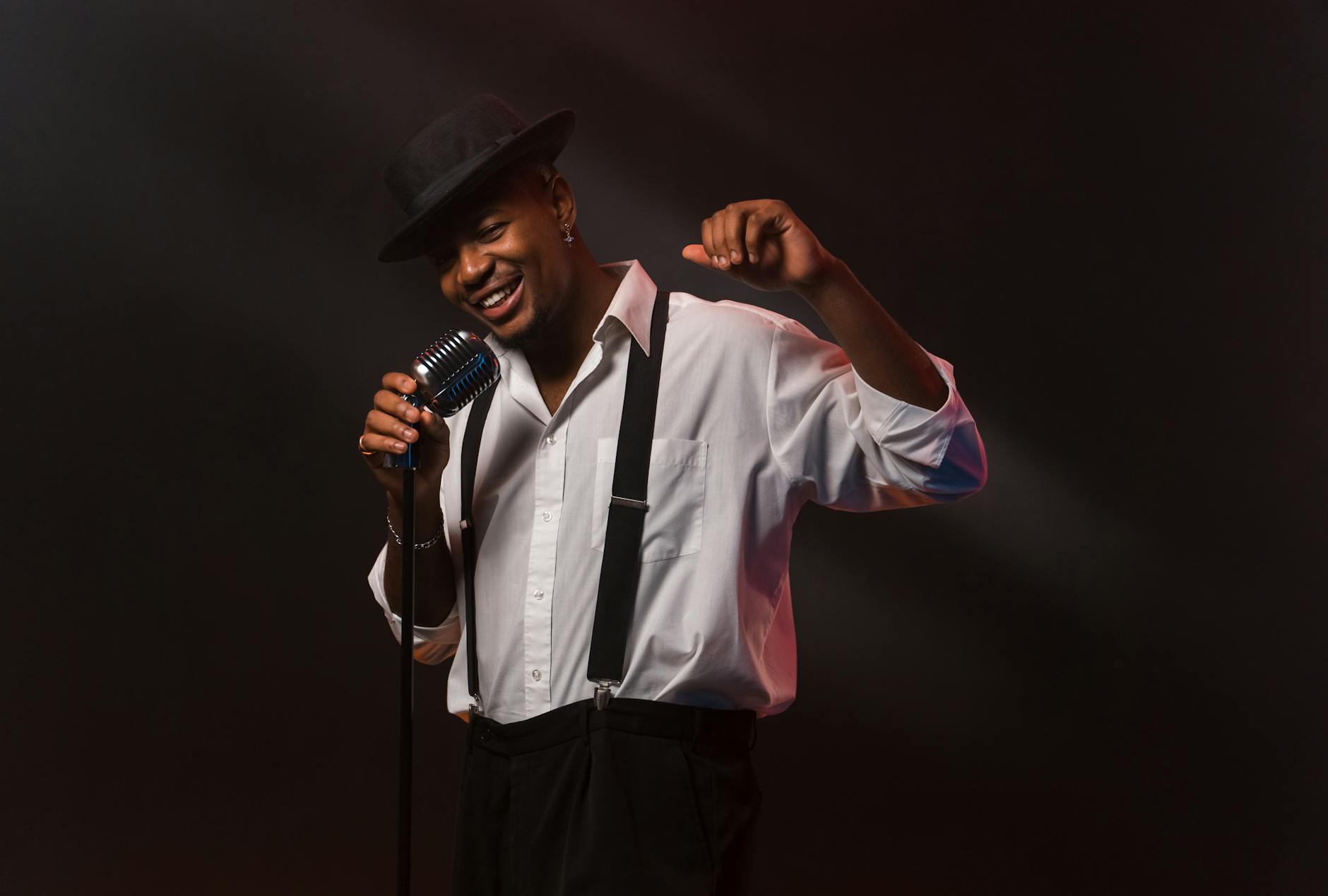 Charismatic man singing with a vintage microphone, showcasing style and passion.