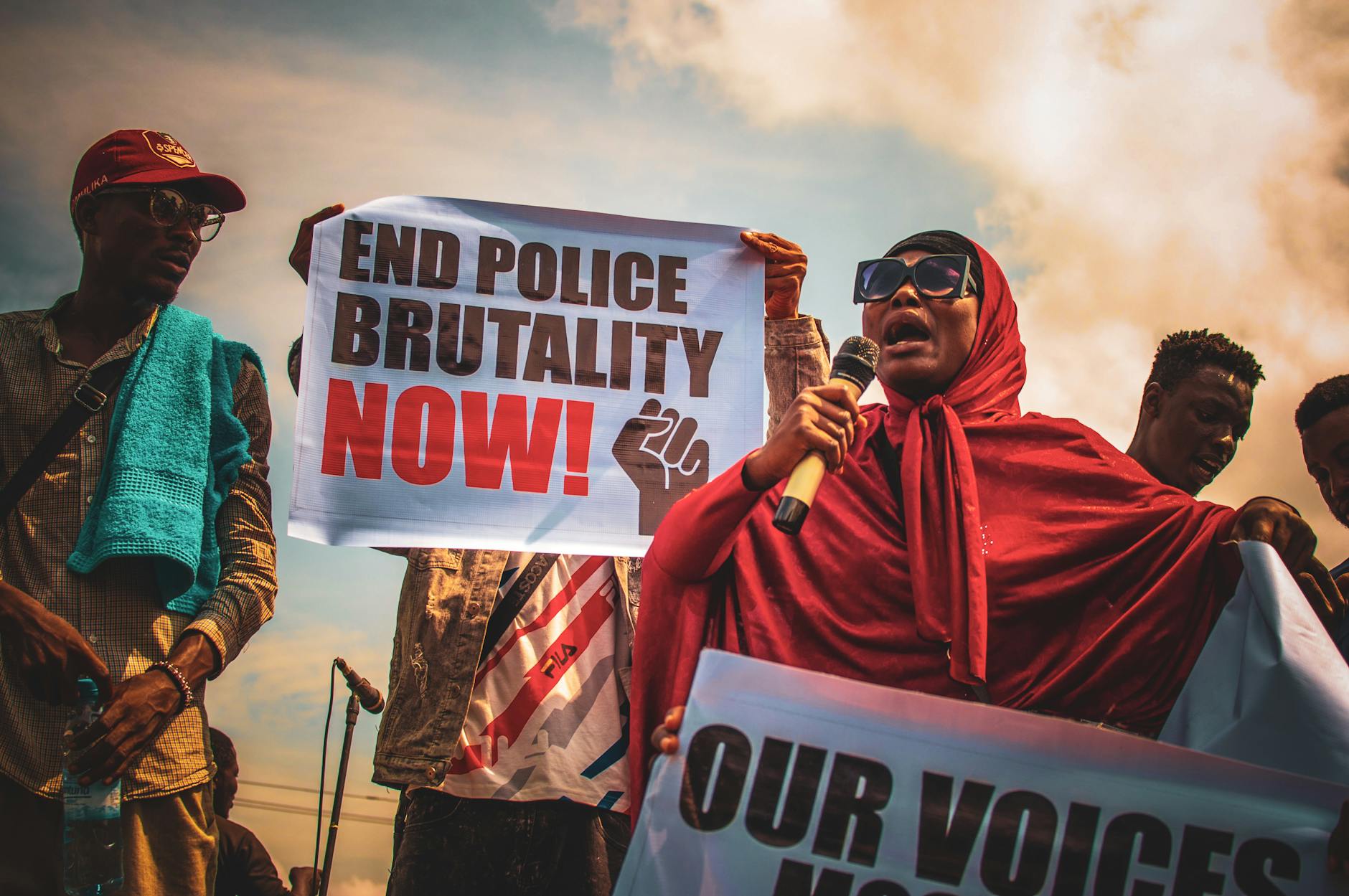Nigerian activists holding signs urging to end police brutality during a peaceful outdoor protest.