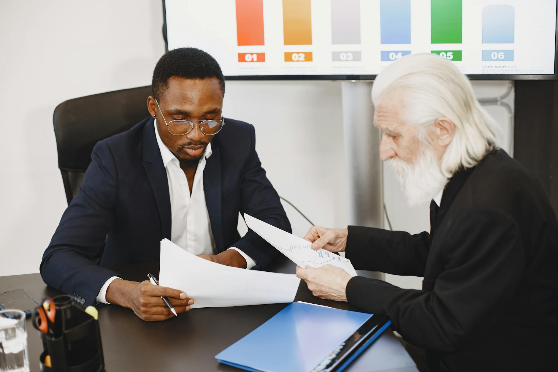 Two businessmen in a meeting discussing documents, focusing on a diverse team engagement.