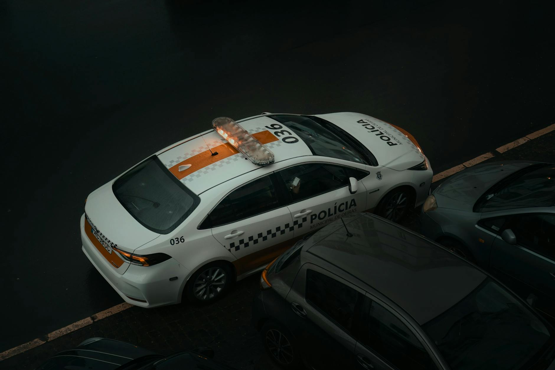 Aerial view of a police car parked on a street in Lisbon, Portugal, during the day.