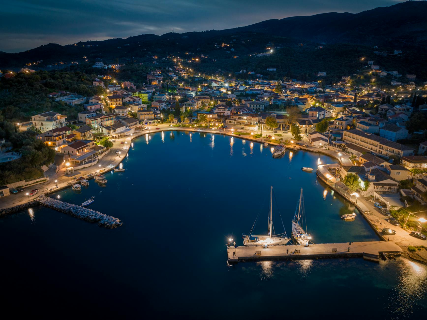 Stunning aerial night view of illuminated harbor and town in Κέρκυρα, Greece.