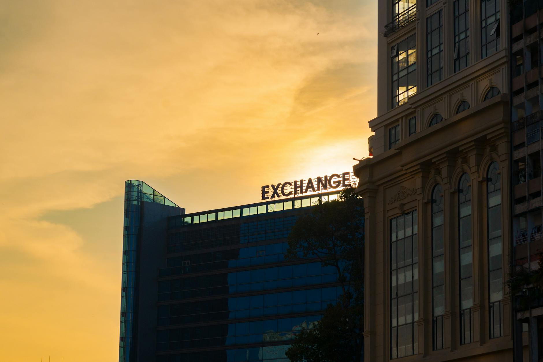 Silhouette of modern office building with 'EXCHANGE' sign during sunset.